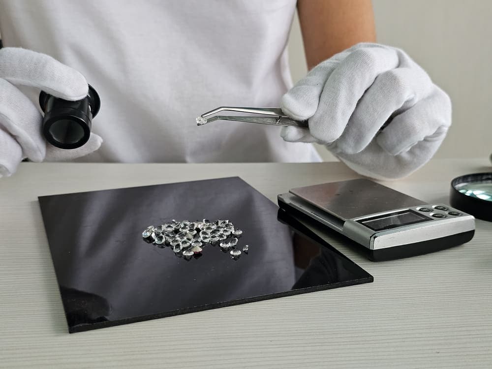 Diamanten werden auf dem Tisch mit Lupe und Waage begutachtet